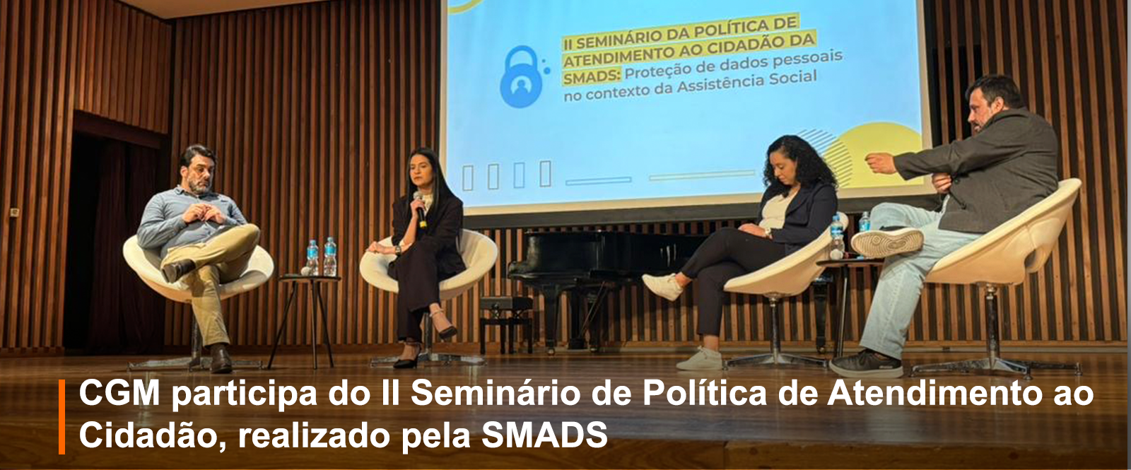 Foto de uma palesta com 4 pessoas no palco