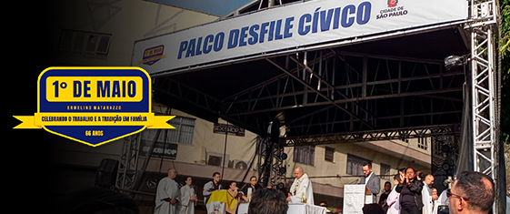 A imagem mostra um palco de estrutura metálica (box truss) com uma faixa branca exibindo os dizeres 