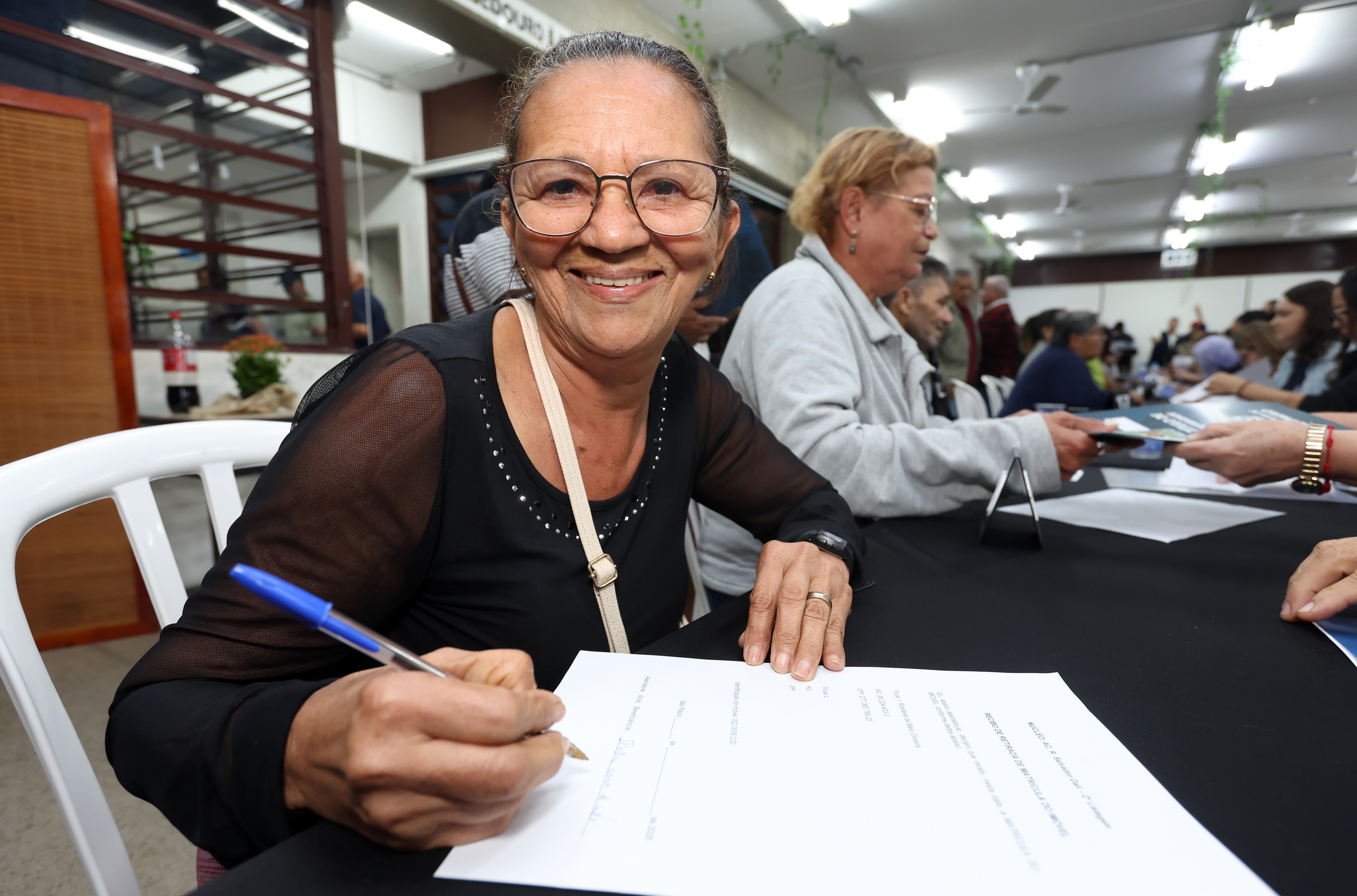 Mulher assina o título de propriedade de seu imóvel