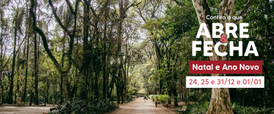 Imagem em formato horizontal de um parque arborizado. Ao centro, há um caminho largo de terra clara que segue em linha reta, cercado por árvores altas e densas dos dois lados, com troncos grossos e copas verdes formando um túnel natural. A luz do dia atravessa as folhas, criando sombras suaves no chão. Ao fundo do caminho, pequenas silhuetas de pessoas aparecem caminhando, bem distantes.  No lado direito da imagem, há um texto informativo sobreposto. Em letras brancas e vermelhas, lê-se: “Confira o que ABRE & FECHA Natal e Ano Novo”. Logo abaixo, em uma faixa vermelha, está escrito: “24, 25 e 31/12 e 01/01”.