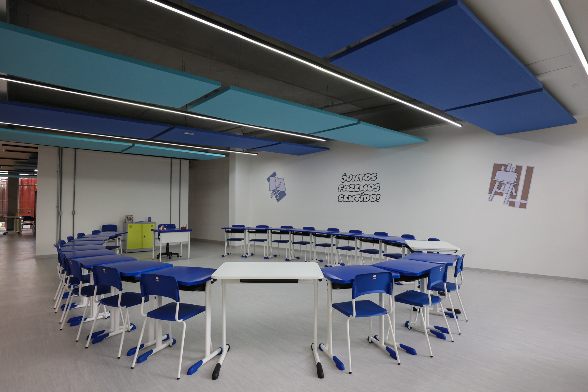 Imagem da sala de oficinas do Centro TEA. Nela há mesas, cadeiras, armários.