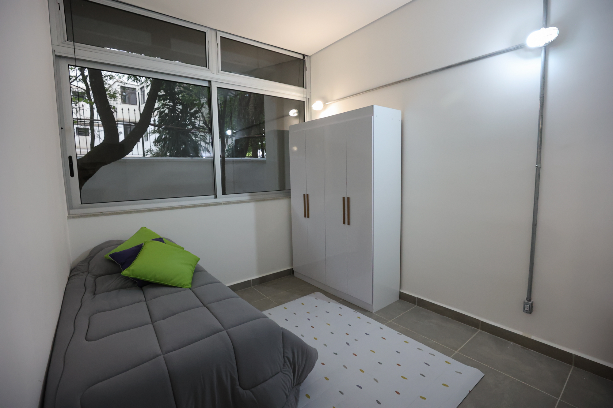 Imagem da sala do Vida Diária do Centro TEA. No quarto há tapete, cama e armário.