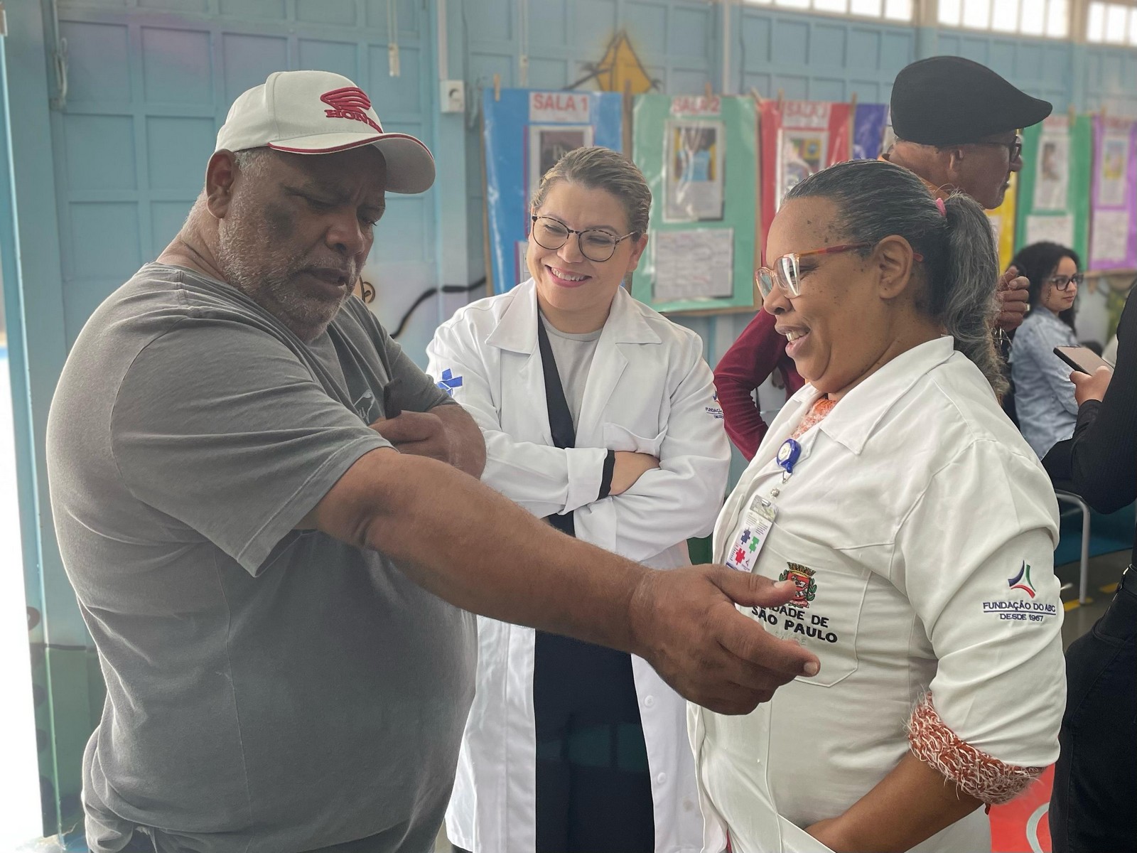 #PraTodosVerem: Duas agentes de saúde uniformizadas conversam com um munícipe durante a ação Gabinete Presente.