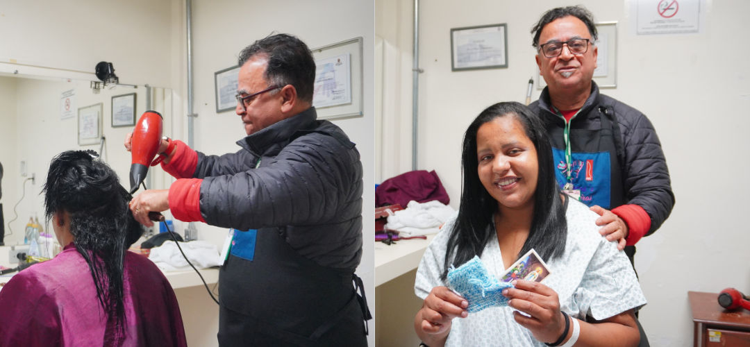 Duas fotos dispostas lado a lado, feitas numa sala clara, com paredes brancas, quadros com certificados na parede e bancada com espelho e objetos de higiene. Ambiente lembra um consultório/hospital.  À esquerda: um Francisco, um homem de cabelo curto escuro com fios grisalhos e óculos, veste jaqueta preta acolchoada por cima de um moletom vermelho e avental. Ele segura um secador vermelho e escova o cabelo de Pâmela, que está sentada de costas. A mulher tem pele negra, cabelo preto úmido e comprido, e usa uma capa de salão roxa sobre os ombros. Vê-se o fio do secador ligado à tomada e itens sobre a bancada.  À direita: Pâmela aparece de frente, sorrindo, já com o cabelo preto escovado, liso e alinhado. Ela usa avental/roupa hospitalar clara e pulseira de identificação no punho. Segura um par de peças de tricô azul e um pequeno santinho. Atrás dela está o mesmo cabeleireiro, de avental, com a mão no ombro da paciente, também sorrindo.