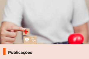 A imagem mostra uma pessoa com uma camiseta branca segurando um quadrado de madeira com simbolos de saúde. Abaixo, uma faixa com o texto 