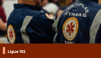 A imagem mostra duas pessoas de costas, vestindo o uniforme do SAMU. Abaixo, uma faixa com o texto 