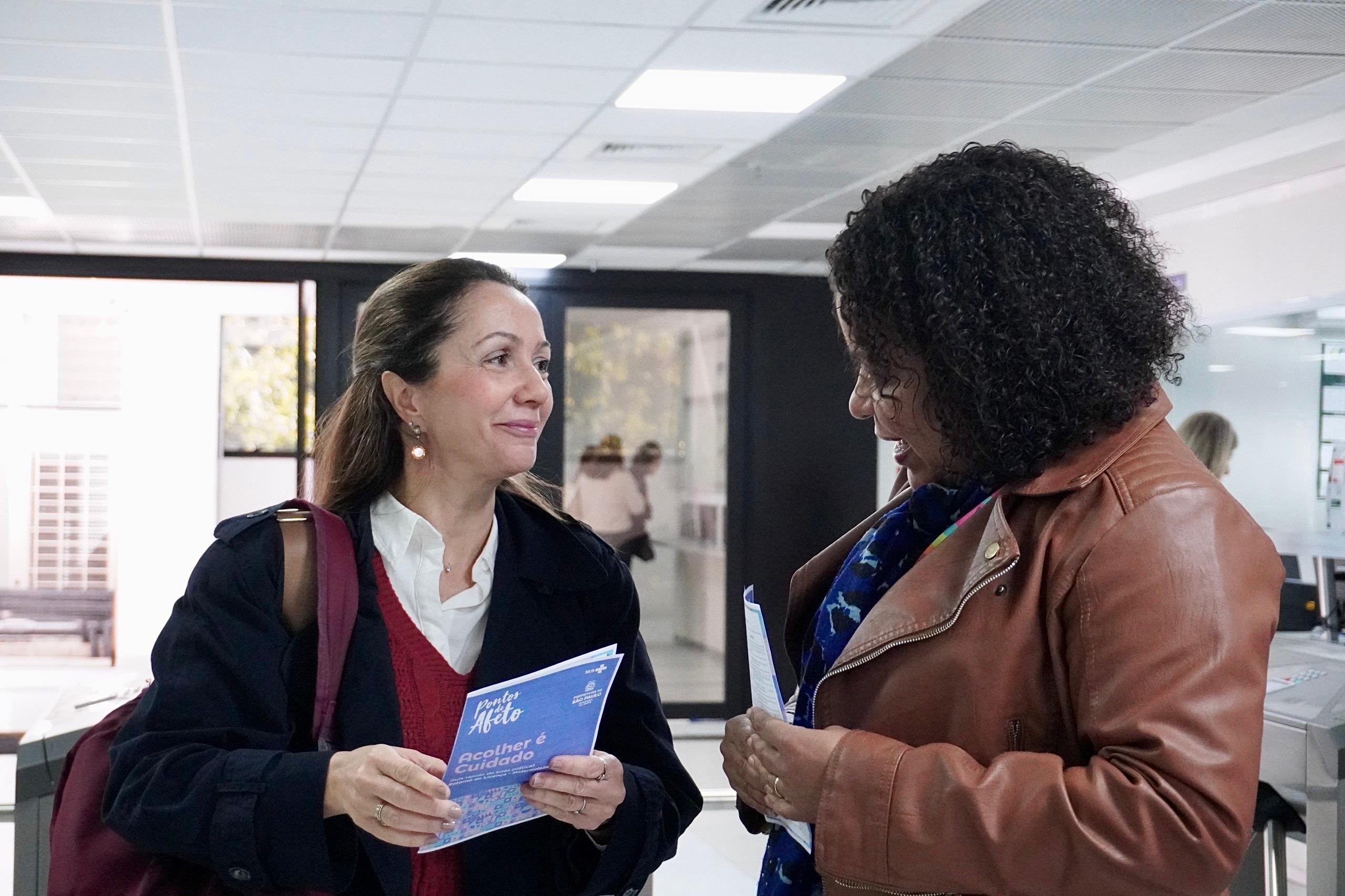 Uma mulher, representante da Equipe do DDCQVT conversa com uma outra servidora pública.