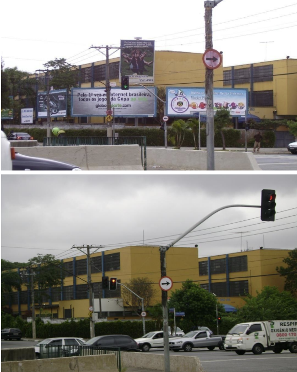 Uma rua em uma área urbana, com placas de publicidade e construções. No topo da imagem, uma grande placa azul escura está posicionada acima de um muro, em frente a um prédio amarelo de dois andares com telhado azul. Em cima do muro, há outra placa de publicidade, um pouco menor. Mais à esquerda, há uma terceira placa. No meio da foto, um semáforo está preso a um poste marrom. Uma placa de trânsito de sentido único em forma de círculo vermelho com uma seta branca apontando para a direita está fixada no mesmo poste. Na parte inferior da foto, há outra foto da mesma área, em um ângulo diferente. A cena apresenta as mesmas construções, mas o semáforo mostra a luz vermelha acesa, indicando que o trânsito está parado. No lado direito da foto, uma van branca está na pista, e no lado esquerdo, um carro preto. Ambas as fotos foram tiradas em um dia nublado.