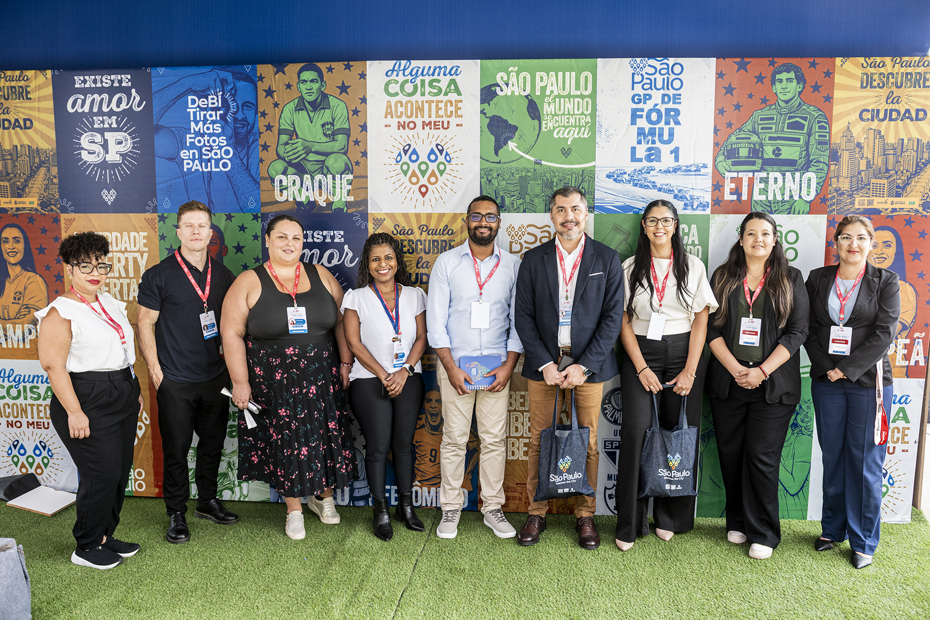 Equipe em frente ao painel de lambe-lambes temáticos, parte do estande da cidade 