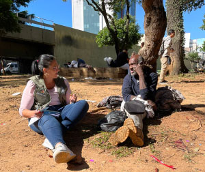 foto de assistente social sentada no chão ao conversando com pessoa em situação de rua